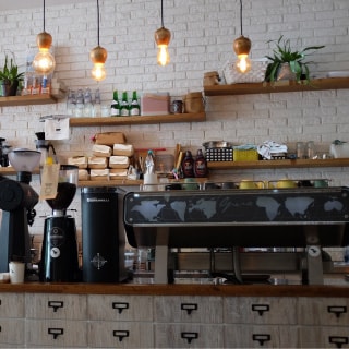 裸電球がぶら下がっているカフェのカウンターの様なところに、コーヒーメーカなどが並んでいる様子